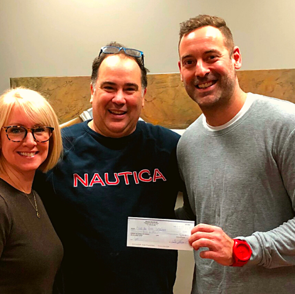 Trois personnes souriantes lors d’une remise de chèque illustrant une collaboration d’équipe au Québec