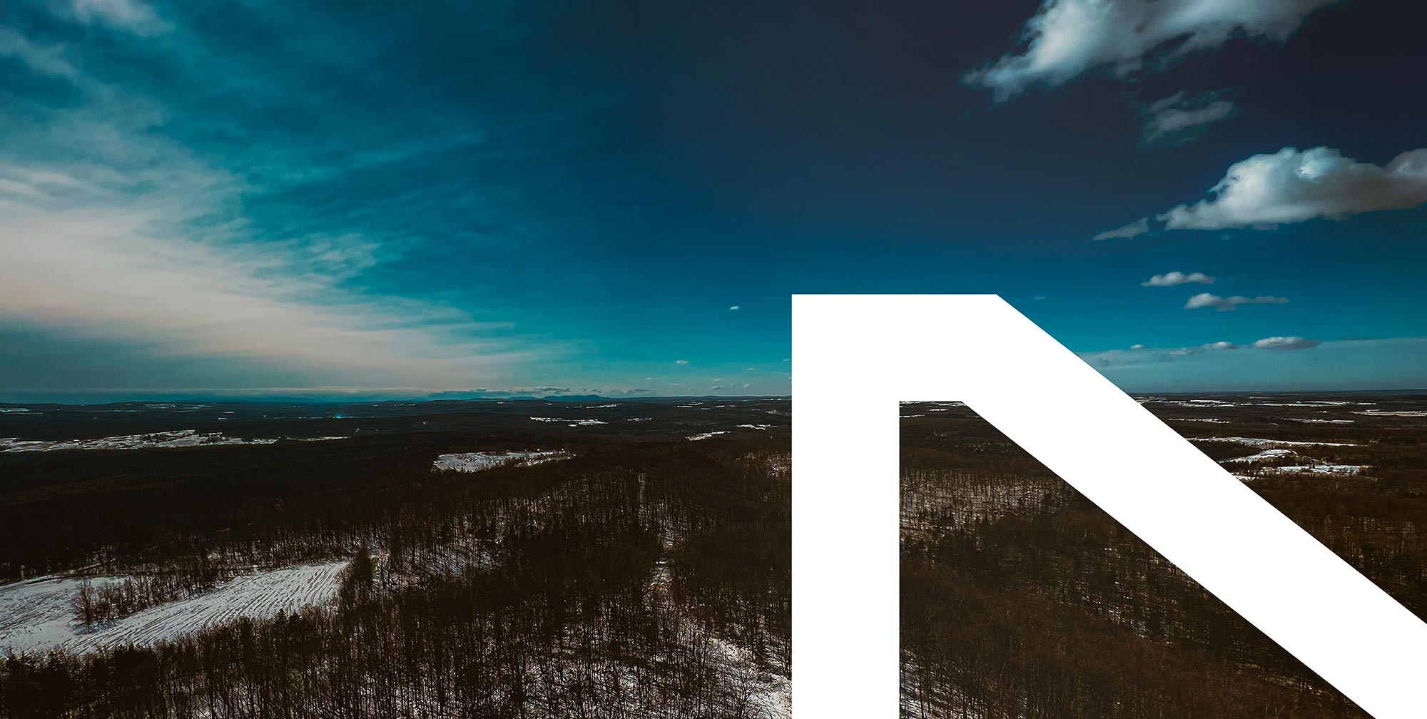 Vue aérienne d’un paysage forestier enneigé au Québec sous un ciel bleu dégagé, panorama naturel hivernal avec horizon étendu